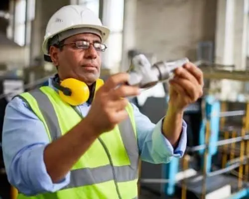 Engineer examining parts in a manufacturing environment.