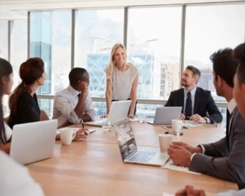 Team at a project kickoff meeting around a large wood conference table in an upscale conference room.