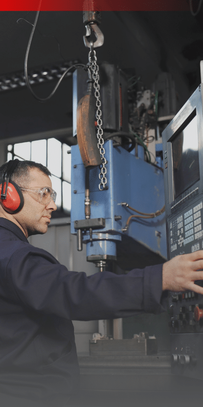 Man wearing hearing protection adjusting a machine on a production floor